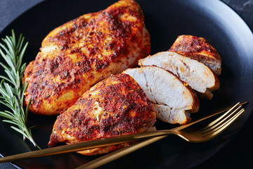 Canvas Print - Spicy baked chicken breasts on a black plate