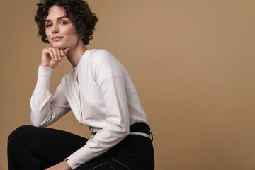 Poster - Image of pleased beautiful woman looking at camera while sitting