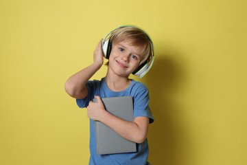 Canvas Print - Cute little boy with headphones listening to audiobook on yellow background