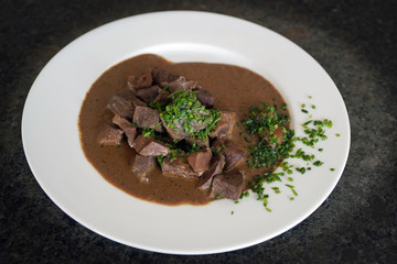 ready to eat, liver, heart and kidneys in sour sauce with chives on a white plate