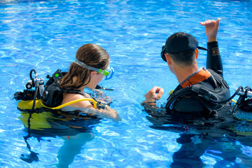 beautiful young woman taking a scuba diving lesson in swimming pool