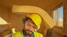 PORTRAIT: Funny Shot Of A Smiling Builder Getting Hit With A Thick Piece Of Foam