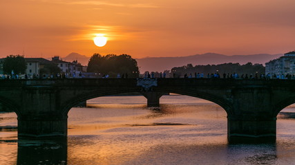 Wall Mural - Cityscape view on Arno river with famous Holy Trinity bridge timelapse on the sunset in Florence