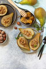 Wall Mural - Healthy diet dessert. Baked pears with hazelnuts, honey and granola on a slate, stone or concrete background. Top view flat lay background. Copy space.