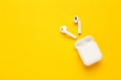 White wireless earphones on yellow background