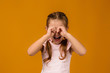© producer - upset little child girl is crying on yellow background. girl wiping tears