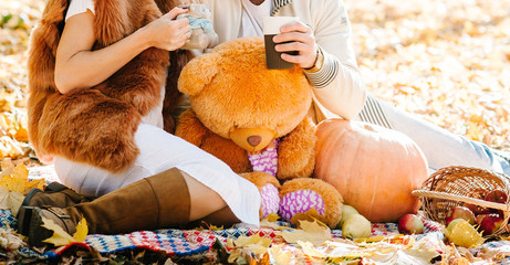  Loving couple: a man and a woman are sitting on a blanket with coffee in the autumn park. Happy people rest on a picnic.
