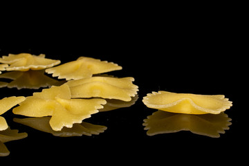 Wall Mural - Group of six whole yellow pasta farfalle isolated on black glass