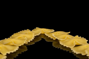 Wall Mural - Lot of whole yellow pasta farfalle isolated on black glass