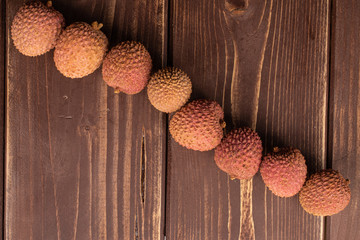 Wall Mural - Group of eight whole fresh lychee flatlay on brown wood