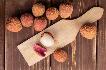 Wall Mural - Group of nine whole one piece of fresh lychee on wooden cutting board flatlay on brown wood