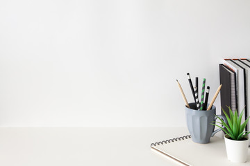 Wall Mural - School desk against an empty white wall. Copy space. School supplies, books, succulent plant and notebook.