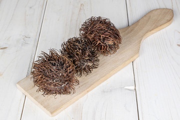 Wall Mural - Group of three whole old brown rambutan on wooden cutting board on white wood