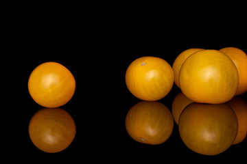 Wall Mural - Group of five whole fresh yellow tomato isolated on black glass