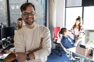 portrait of senior programmer and group leader.he standing at the office in front of his workers.
