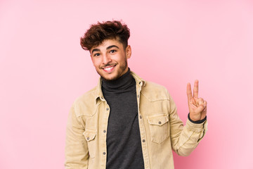 Young arabian man posing in a background isolated showing victory sign and smiling broadly.