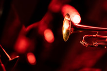 A Trumpet Player Playing The Trumpet In A Big Band Concert On Stage With Red Stage Lights With Bokeh In The Background