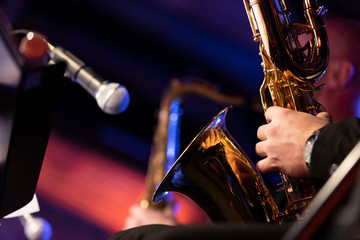 A baritone saxophone player of a big band playing his instrument with a microphone pointed at the bell of the instrument