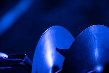 A Pair Of Crash Cymbals In A Rack Waiting To Be Played By An Orchestra Musician On Stage Of Blue Lights