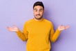 Young caucasian man isolated on purple background confused and doubtful shrugging shoulders to hold a copy space.