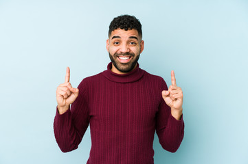 Young mixed race arabic man isolated indicates with both fore fingers up showing a blank space.