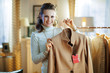 © Alliance - happy elegant woman holding beige coat with sale price tag