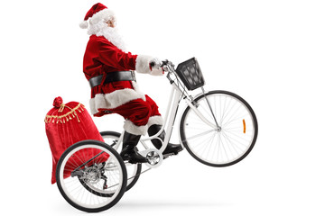 Canvas Print - Santa claus riding a white tricycle on one wheel