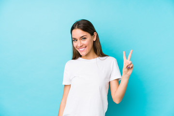 Wall Mural - Young caucasian woman  isolated showing victory sign and smiling broadly.