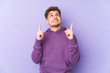 © Asier - Young blond curly hair caucasian man isolated pointing upside with opened mouth.