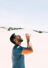 Thirsty African Man Drinking Water In The Desert To Calm Thirst And Heatwave