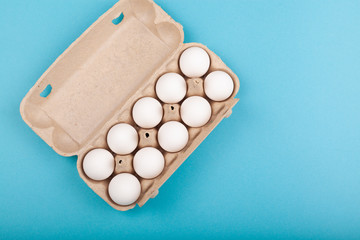 Egg Chicken eggs. Top view of an open gray box with white eggs. Isolated on a blue background. The concept of a healthy lifestyle, getting pure protein. Proper Breakfast. Preparing for Easter.