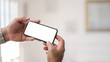 © bongkarn - Close up view of businessman holding horizontal smartphone in simple office room