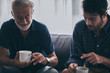 © chokniti - Father-son bonding. Cheerful young man drinking coffee together with him