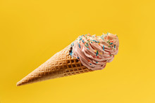 Ice Cream In A Waffle Cone Isolated On A Bright Yellow Background. Marshmallow Cake In A Waffle Cone. Falling Cake Colored With Colored Sugar Sprinkles.