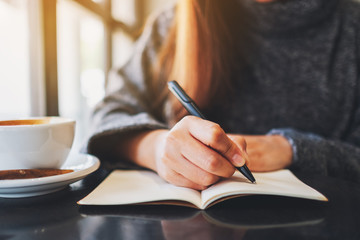 Closeup image of a woman writing on a blank notebook on the table