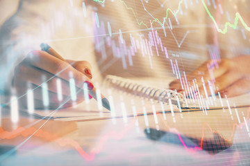 Double exposure of woman's hands making notes with forex graph hologram. Concept stock market analysis.