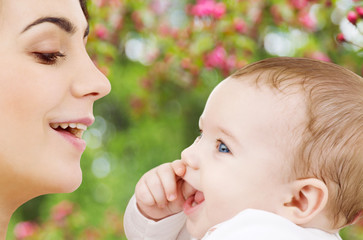 Canvas Print - family and motherhood concept - happy smiling young mother with little baby over natural spring cherry blossom background