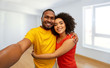 © Syda Productions - new home, real estate and people concept - happy smiling african american couple taking selfie over empty apartment on background