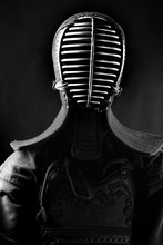 Kendo Fighter Masked Portrait In Full Uniform On A Black Background Silhouette. In A Mask For Fencing. Black And White Photo