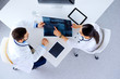 © khmelev - Medical team of doctors sitting and discussing about x-ray at table with tablets, top view