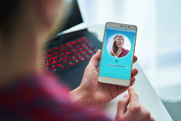 Female unlocking smartphone using facial recognition system. Biometric verification identification and face id scanning. High tech technology