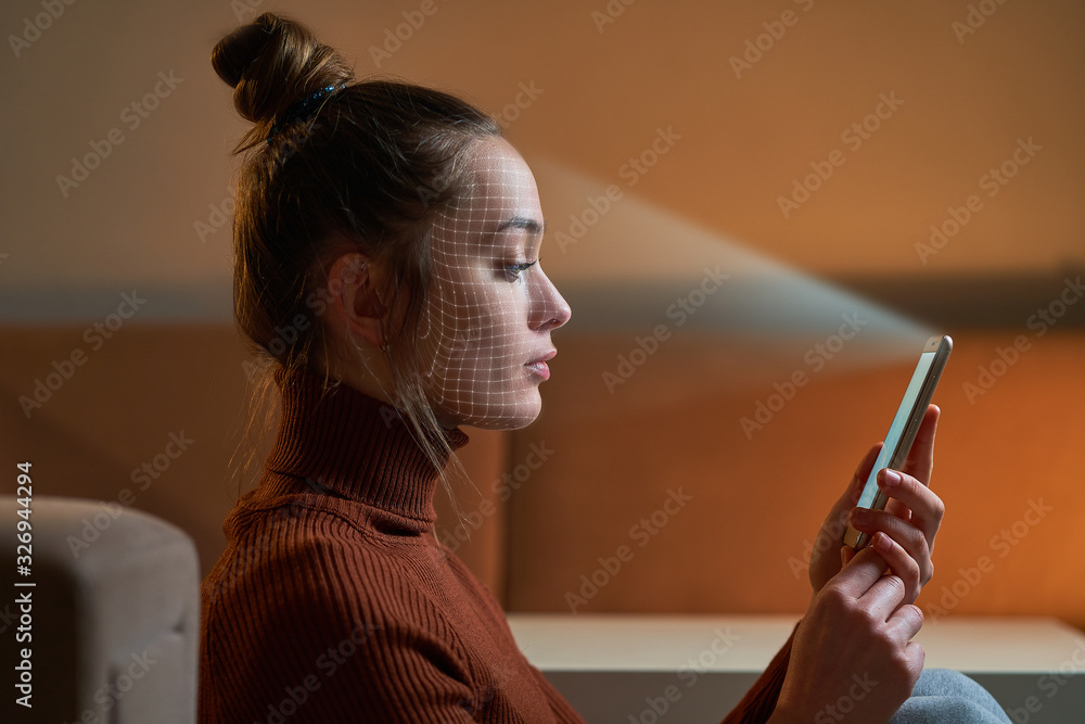 Female scans face using facial recognition system on smartphone for biometric identification. Future digital high tech technology and face id - obrazy, fototapety, plakaty 