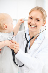 Doctor and patient in hospital. Little girl dressed in grey dress is being examined by doctor with stethoscope. Medicine concept