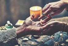 Fortune Teller Woman Wearing Silver Rings With Turquoise Stone And Bracelets Reads Palm Lines During Fortune Telling Around Candles And Other Magic Accessories. Palmistry And Occult Divination
