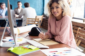 Wall Mural - Portrait of a happy casual businesswoman sitting at her workplace in office