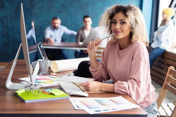 Canvas Print - Portrait of a happy casual businesswoman sitting at her workplace in office