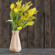 tulips and mimosa in vase on dark wooden background