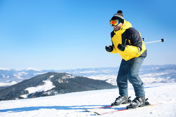 Wall Mural - Young man skiing on hill, space for text. Winter vacation