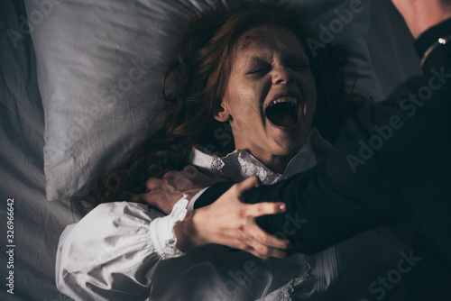 Cuadros en Lienzo exorcist holding yelling female demon in bed