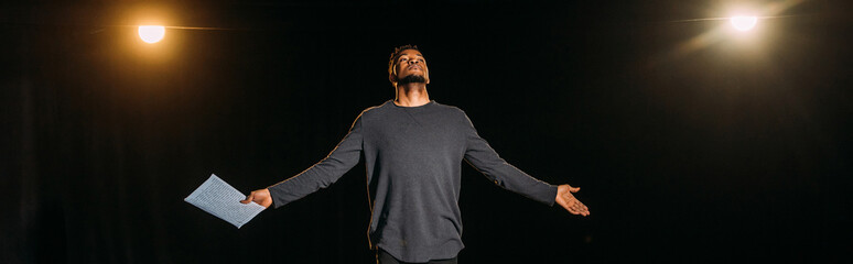 panoramic shot of african american actor holding scenario and standing on stage during rehearse